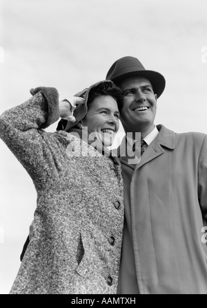 Années 1950 DANS DEUX CHAPEAUX & MANTEAUX AVEC LES BRAS AUTOUR DE L'AUTRE À DISTANCE EN OFF Banque D'Images