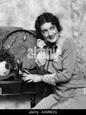 Années 1920 Années 1930 WOMAN ON PHONE ASSIS PAR TABLE AVEC PLAQUE DÉCORATIVE TÉLÉPHONE PANIER NAVAJO & FLOWERS SMILING Banque D'Images