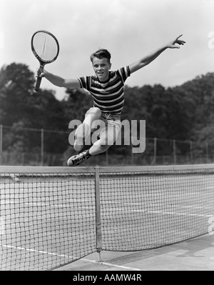 1930 TEENAGE BOY JUMPING TENNIS RACKET AVEC NET DANS LA MAIN Banque D'Images