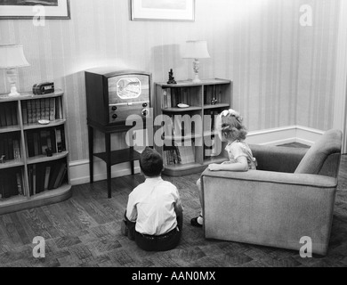 Années 1940 Années 1950 Garçon et fille avec dos à l'Observateur d'événements dans la salle de séjour en regardant un petit écran Banque D'Images