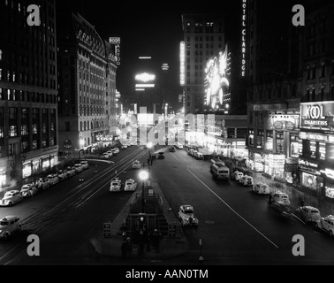 1930 Passage de TIMES SQUARE ÉCLAIRÉ LA NUIT AVEC DES VOITURES DE BAS DE BORDURES Banque D'Images