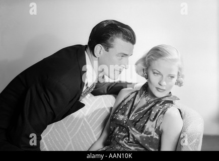 1950 COUPLE AVEC LA FEMME assise à l'écart l'homme aux cheveux blonds À PROFIL SATIN bien habillé Banque D'Images