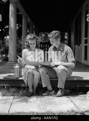 Années 1940 Années 1950 HOMME FEMME COUPLE ASSIS LECTURE Porche Banque D'Images