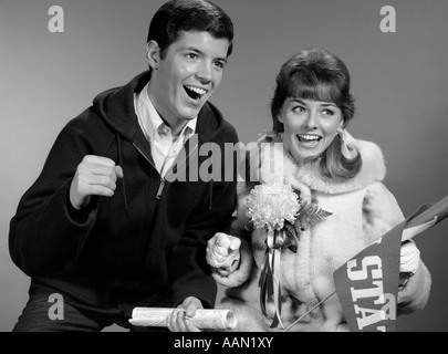 1960 PORTRAIT DE COUPLE CHEERING JEU ELLE AVEC UN FANION & CORSAGE Banque D'Images