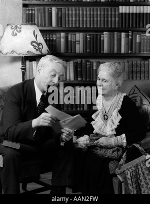 Années 1930 Années 1940 A PRIS SA RETRAITE COUPLE VÉRIFIER DANS LA SALLE DE SÉJOUR MAN SMOKING PIPE Banque D'Images