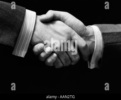 Années 1930 close-up d'hommes d'AFFAIRES DANS LES MAINS SUR UN FOND SOMBRE HANDSHAKE Banque D'Images