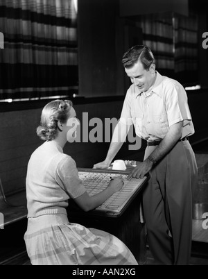 1950 COUPLE LOOKING AT BOWLING SCORECARD Banque D'Images