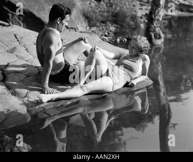 1930 MAN SUR DES ROCHERS PRÈS DE L'eau portant des maillots de Banque D'Images