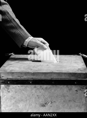 Années 1930 Années 1940 LA MAIN DE L'HOMME METTRE DANS L'EMPLACEMENT DE VOTE DANS LA CASE Banque D'Images