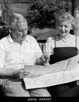 1950 Couple âgé ASSIS SUR UN BANC EN REGARDANT LA CARTE Banque D'Images