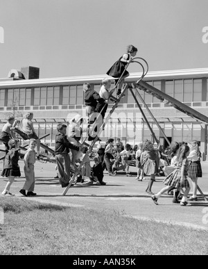 1950 AIRE DE JEUX DE L'ÉCOLE ÉLÉMENTAIRE À LA RÉCRÉATION AVEC LA LIGNE D'ENFANTS escalier de remonte de la diapositive Banque D'Images