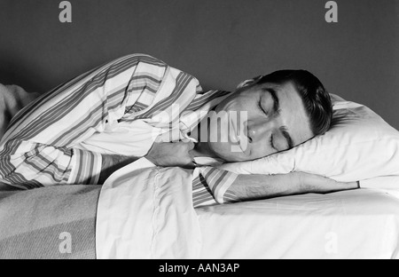 Années 1950 Années 1960 L'HOMME EN pyjama rayé SMILING ENDORMI DANS LE LIT Banque D'Images