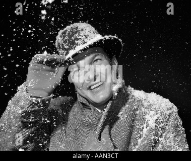 Années 1950 Années 1960 SMILING MAN IN HAT EXTÉRIEUR PARDESSUS ET DES GANTS PENDANT L'enneigement Banque D'Images