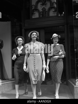 1930 TROIS FEMMES HABILLÉES À LA MODE SOURIRE SHOPPING À PIED DE MAGASIN DE VENTE AU DÉTAIL Banque D'Images