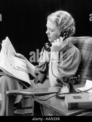 Années 1920 Années 1930 YOUNG WOMAN SITTING IN CHAIR À LA RECHERCHE DE JOURNAUX À Banque D'Images