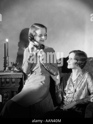 Années 1920 Années 1930 DEUX FEMMES L'un parlant au téléphone AUTRES SITTING IN CHAIR Candle Light Banque D'Images