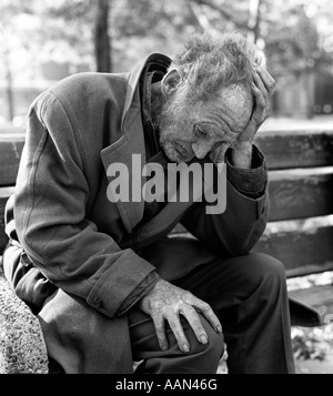 1970 personnes âgées indigentes MAN SITTING ON PARK BENCH WITH HEAD IN HANDS OUTDOOR Banque D'Images