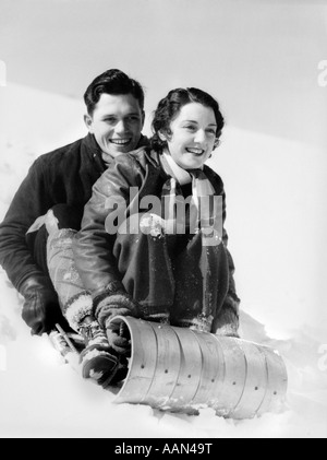 Années 1920 Années 1930 SMILING COUPLE Homme et femme sur la luge en hiver Banque D'Images