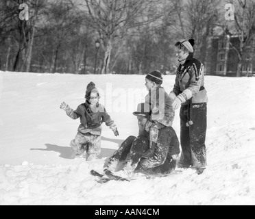 1930 MAN & WOMAN WITH A Boy & GIRL habillé en vêtements d'HIVER JOUER AVEC SLED IN SNOWY FIELD Banque D'Images