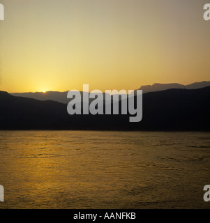 Vue sur le fleuve au coucher du soleil avec le paysage au-delà de la silhouette sur un ciel d'or Chine Sichuan Banque D'Images