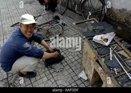 Chine Shanxi Datong homme réparer le tube pneu d'une bicyclette sur le trottoir Banque D'Images