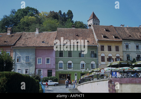 Maisons peintes de couleurs vives dans la ville médiévale de Sighisoara en dessous de l'Église sur la Colline perché au-dessus de la Roumanie Banque D'Images