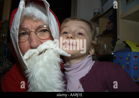 Grand-mère en costume père noël d'être embrassé par sa petite-fille Banque D'Images
