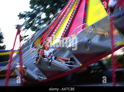 Les enfants hurlent de plaisir sur un tour à la fête foraine Banque D'Images