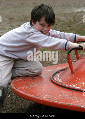 Jeune garçon jouant sur un merry go round Banque D'Images