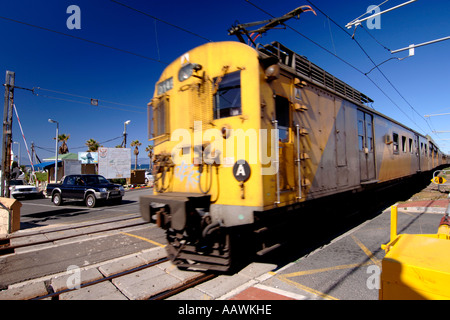 Un train allant au-delà d'un passage à niveau du port de Kalk Bay à Cape Town, Afrique du Sud. Banque D'Images
