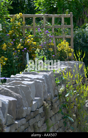 Mur de pierres sèches en pierre sèche communes bord de jardin avec trellis verbascum avec des roses Banque D'Images