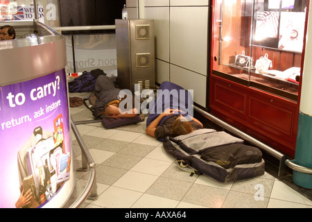 Les passagers endormis sur le sol à l'aéroport de Gatwick, en raison de retards des vols de vacances. Banque D'Images