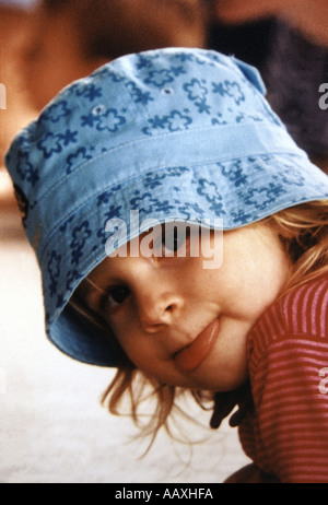 Petite fille au chapeau bleu se pencher en avant son collage hors de la langue étant très sassy Banque D'Images