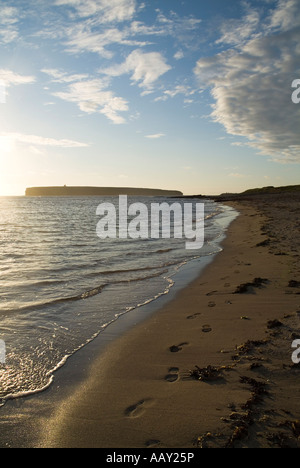 Dh Birsay Bay BIRSAY ORKNEY empreintes de pas dans le sable le long de la plage coucher du soleil mer Brough de Birsay Banque D'Images