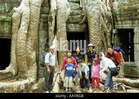 Groupe de touristes asiatiques posant devant le Banyan Tree roots croissant sur le Ta Prohm temple, Cambodge Banque D'Images