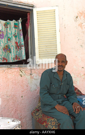 L'homme égyptien assis sur table avec tapis sur il vieille ville Ed Dahar région Hurghada Banque D'Images