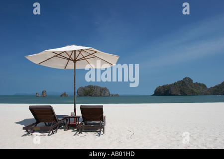 Deux fauteuils vacants sous un parasol blanc sur la plage de Tanjung Rhu. L'île de Langkawi, Malaisie. Banque D'Images