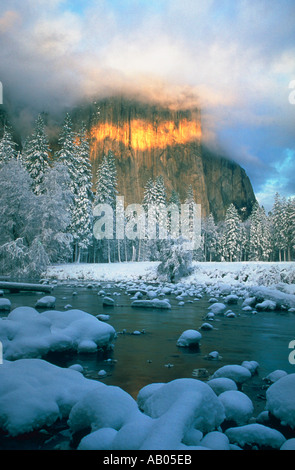 El Capitan s'élève dans les nuages au-dessus d'arbres couverts de neige et la rivière Merced Yosemite National Park en Californie Banque D'Images