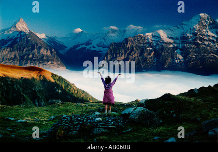 Femme debout avec une veste autour de sa taille et ses mains posées sur les nuages en Grindelwald Suisse Banque D'Images