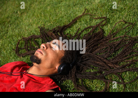 Man laying in grass listening to headphones Banque D'Images