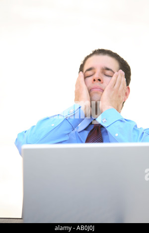 Young businessman working on laptop avec regard frustré sur le visage Banque D'Images
