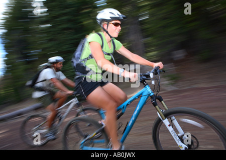 Jeune couple mountain biking together with blurred motion Banque D'Images