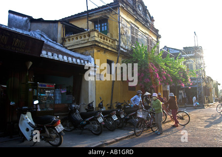 Coin de rue avec des vélos et des bougainvillées de germination jaune pastel bâtiment colonial de la ville historique de Hoi An milieu Vietnam Banque D'Images