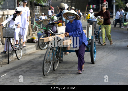 Femme au chapeau conique poussant location et remorque avec bois sur Cam Nam ridge ville historique de Hoi An milieu Vietnam Banque D'Images