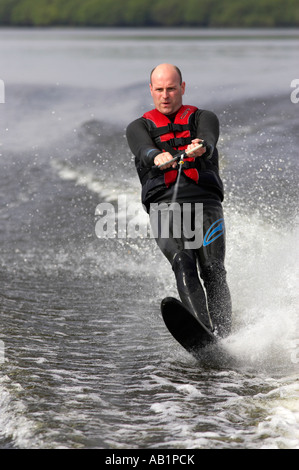 La mi 30s mâle dans la combinaison du ski nautique se concentrant sur un seul disque coupant à travers le voile ski service Banque D'Images