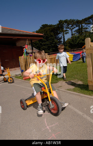 Ysgol Gymraeg Aberystwyth gallois les élèves de l'école primaire joue dehors au soleil sur tricycle Banque D'Images