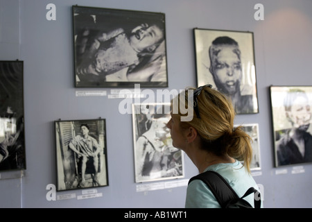 Jeune femme examine des photos explicites de la guerre du Vietnam dans le Musée des débris de guerre Ho Chi Minh City Vietnam Banque D'Images