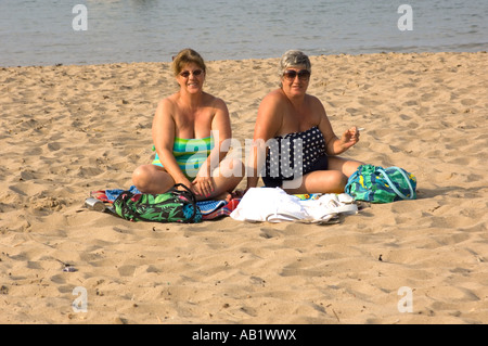 Deux femmes ayant un excès de graisse (deux femmes) sur une plage de sable l'un avec une cigarette dans la main gauche, après-midi d'été Banque D'Images