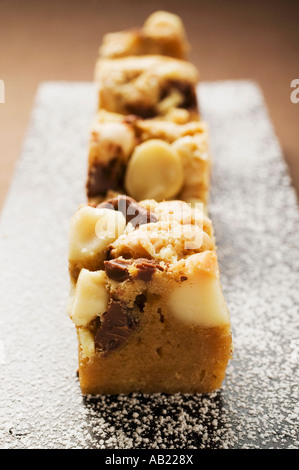 Les petits morceaux de chocolat coupe avec les noix de macadamia à bord FoodCollection Banque D'Images