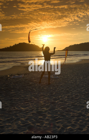 Jeune femme maillot de twirling poi rubans dans coucher du soleil plage de Palolem sud de Goa Inde Banque D'Images